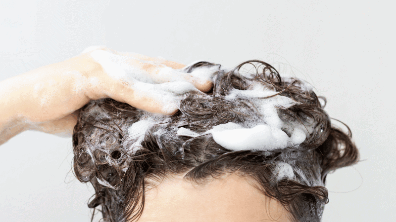 woman shampooing hair using shampoo for low porosity with sodium c14-16 olefin sulfonate