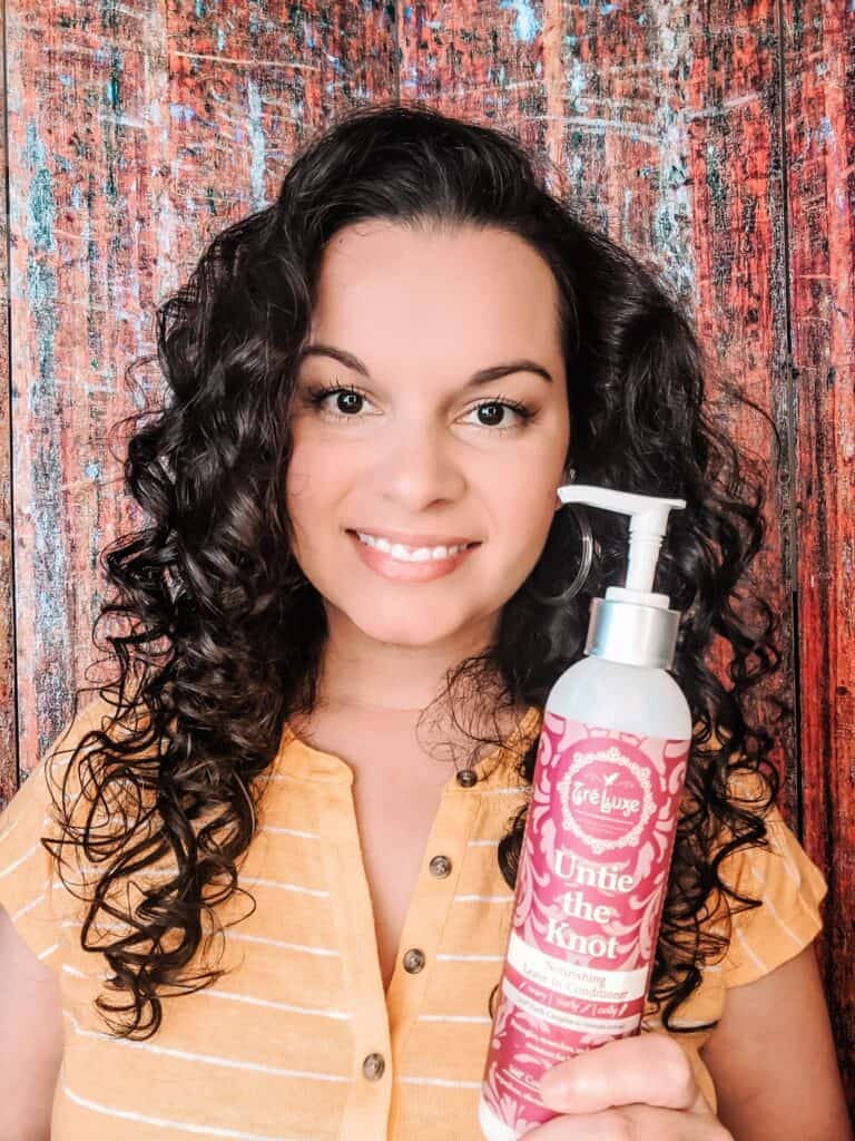 holding up the TreLuxe conditioner for curly hair showing my styled curls. This is a curly girl method approved conditioner.